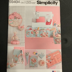 May include: A Simplicity S9404 sewing pattern envelope featuring illustrations of various fabric organizers, including a sewing machine cover, a pincushion, a scissor case, and a needle book, all decorated with floral patterns in shades of pink and blue.