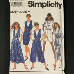 May include: A Simplicity sewing pattern packet, size AA, featuring illustrations of five different outfits. The packet has the number 7877 and the words "easy to sew" printed on it. The outfits include dresses and jumpsuits in various patterns.