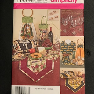 May include: A Simplicity 1483 sewing pattern envelope featuring illustrations of kitchen and dining accessories including a hanging towel, wine bottle bag, table runner, and bowl cover with wine and grape motifs, plus Green Bay Packers themed items.