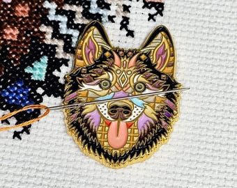 May include: A gold-coloured metal pin featuring a detailed design of a wolf's face. The wolf has a black, white, pink, and blue patterned design. The wolf's tongue is sticking out.