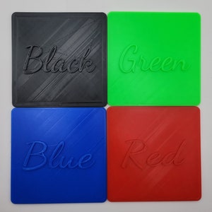 Puede incluir: Cuatro posavasos cuadrados en negro, verde, azul y rojo. Cada posavasos presenta una inscripci&oacute;n en relieve en letra cursiva en el centro que coincide con su color base. El negro dice Black, el verde Green, el azul Blue y el rojo Red.