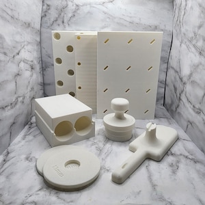 May include: A set of white plastic tools for making polymer clay earrings. The set includes a variety of tools, including a stamp, a cutter, a roller, and a mold. The tools are all made of white plastic and have a smooth finish.
