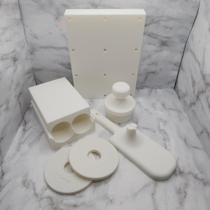 May include: White plastic mold for making donuts, with a plunger, a cutter, and two donut rings. The rings are labeled "13mm".