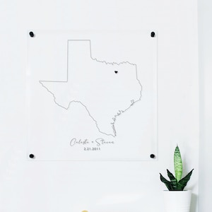 This is a clear acrylic sign with an outline of the state of Texas and a heart displaying where a couple met. Personalized map art with name and date.