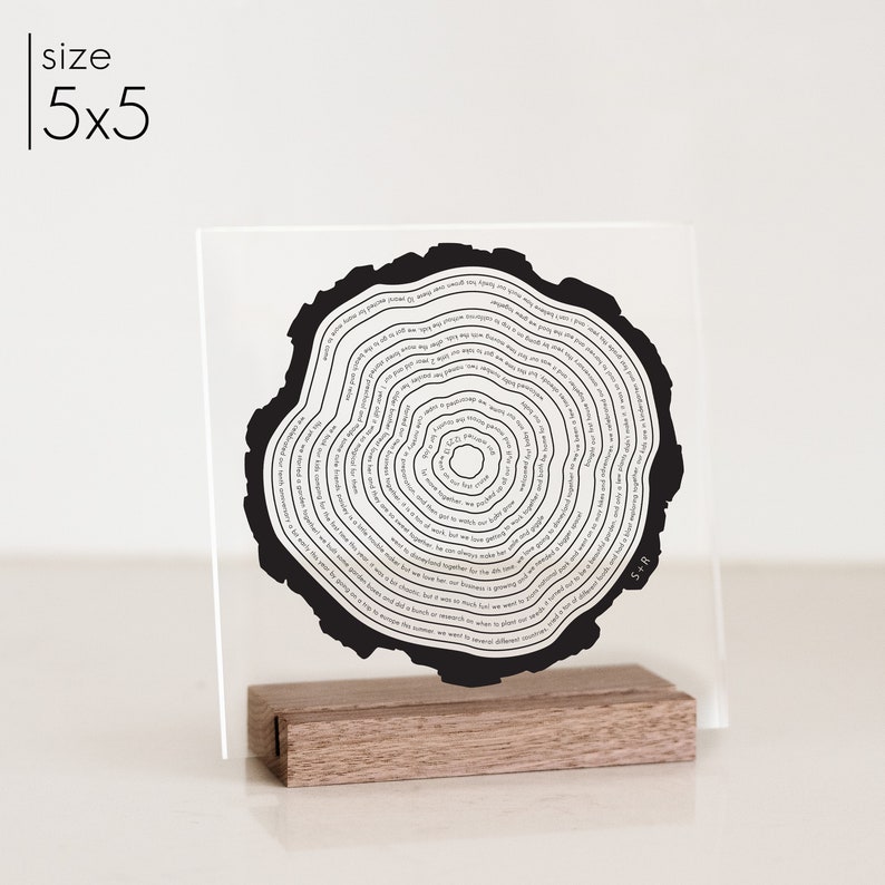 Acrylic tree ring art sign that is printed in black and has a wood stand.