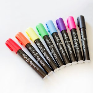 Red, orange, yellow, green, blue, purple, pink neon chalk markers with black chalk marker.