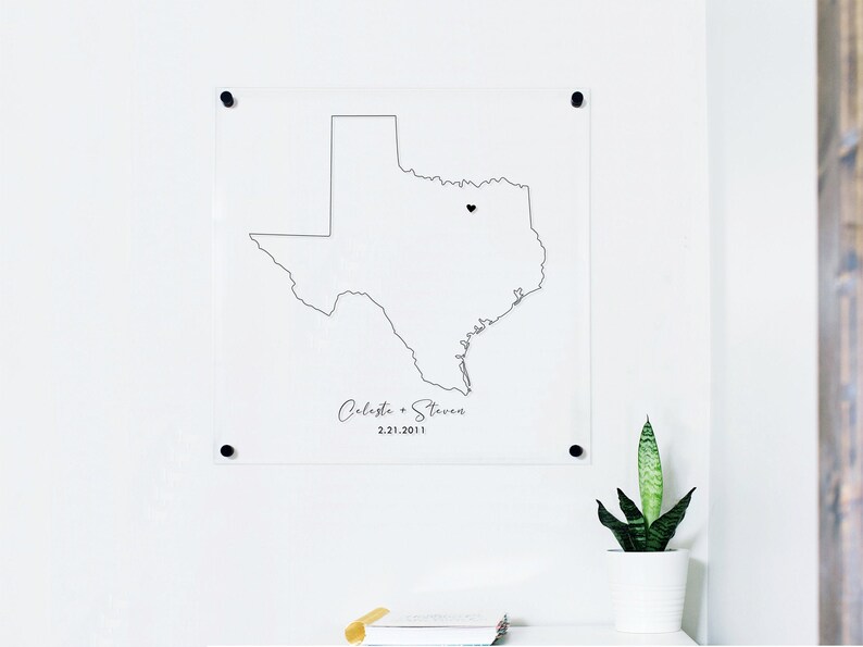 This is a clear acrylic sign with an outline of the state of Texas and a heart displaying where a couple met. Personalized map art with name and date.