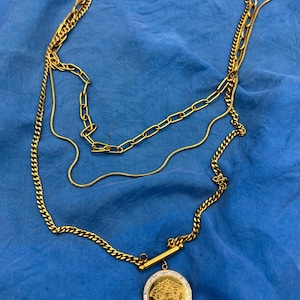 Gold tone tri-chain 22 inch necklace with medusa coin, paperclip chain and round snake chain. - Free Shipping