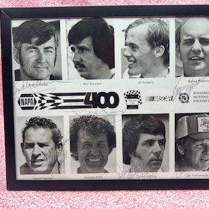May include: Black and white photo of eight race car drivers, including Bobby Allison, Neil Bonnett, Al Holbert, and Benny Parsons. The photo is signed by each driver and includes the text "Riverside International Raceway" and "NAPA 400".