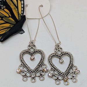 Puede incluir: Pendientes de corazón colgantes de plata con detalles de cristal transparente.