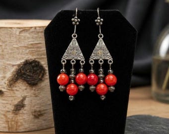 Brincos tribais em prata de lei com coral vermelho, apresentando intrincado trabalho de filigrana e contas pendentes.