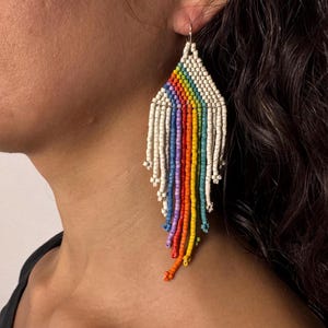 May include: Rainbow beaded earrings with white beads and a fringe design.