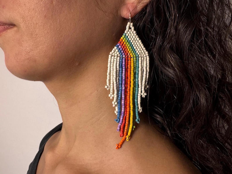 May include: Rainbow beaded earrings with white beads and a fringe design.