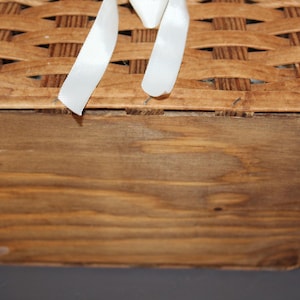 May include: The bottom of a wooden basket with a woven top. The basket is made of natural wood and has a light brown color. The basket is empty.