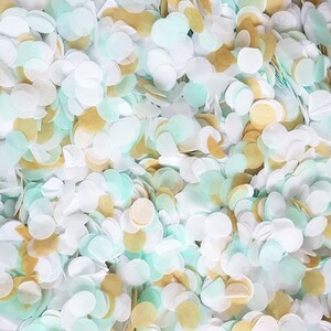 Peut inclure: Un tas de confettis de couleur blanche, bleu clair et or. Les confettis sont en papier et ont la forme de cercles.
