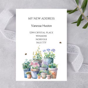 May include: A watercolour design featuring potted plants with flowers and greenery. The text "MY NEW ADDRESS" is at the top, followed by a name and address. Two small bees are also included in the design.