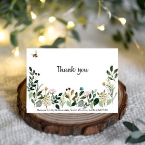 May include: A rectangular white card featuring the text Thank you in black script, decorated with watercolour illustrations of green foliage, small flowers, and a bee. The bottom includes the text Melanie Smith, 24 Riverdale, South Moulton, Norfolk, NR7 5TR.