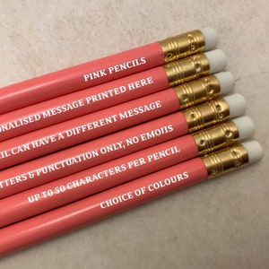 May include: Pink pencils with a gold band and white eraser. The pencils have a personalized message printed on them. The message reads: "PINK PENCILS PERSONALISED MESSAGE PRINTED HERE EACH PENCIL CAN HAVE A DIFFERENT MESSAGE CAPITAL LETTERS & PUNCTUATION ONLY, NO EMOJIS UP TO 50 CHARACTERS PER PENCIL CHOICE OF COLOURS".
