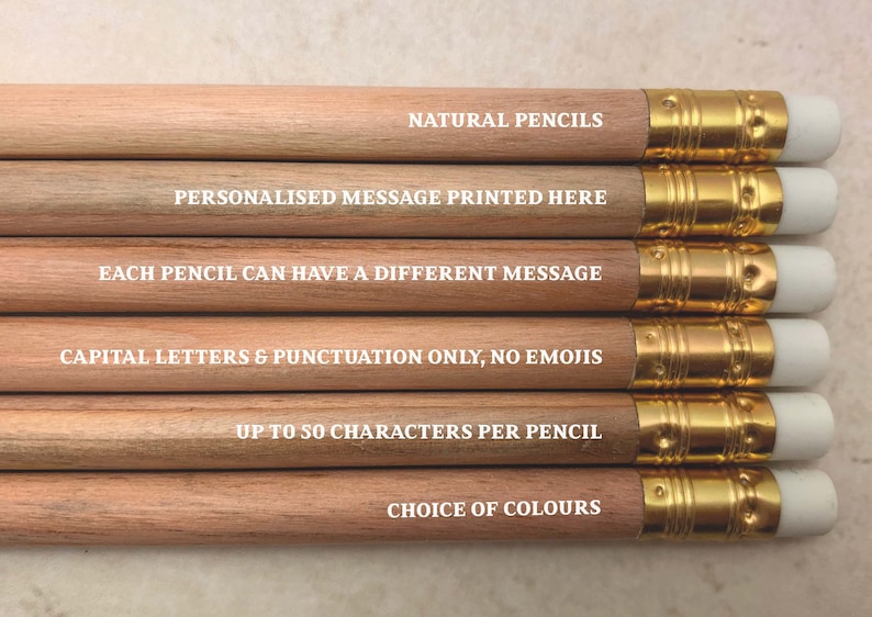 May include: A set of natural wood pencils with gold-colored metal tips and white erasers. Each pencil has a different message printed on it in white letters. The messages are: "NATURAL PENCILS", "PERSONALISED MESSAGE PRINTED HERE", "EACH PENCIL CAN HAVE A DIFFERENT MESSAGE", "CAPITAL LETTERS & PUNCTUATION ONLY, NO EMOJIS", "UP TO 50 CHARACTERS PER PENCIL", and "CHOICE OF COLOURS".