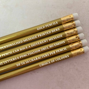 May include: Gold pencils with white erasers. Each pencil can have a personalized message printed on it. The text reads "GOLD PENCILS", "PERSONALISED MESSAGE PRINTED HERE", "EACH PENCIL CAN HAVE A DIFFERENT MESSAGE", "CAPITAL LETTERS & PUNCTUATION ONLY, NO EMOJIS", "UP TO 50 CHARACTERS PER PENCIL", and "CHOICE OF COLOURS".