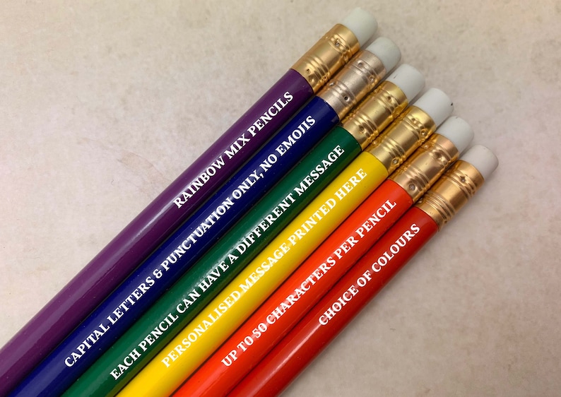 May include: Six rainbow colored pencils with white erasers and gold trim. Each pencil has a different message printed on it in white letters. The messages are: "Rainbow Mix Pencils", "Capital Letters & Punctuation Only, No Emojis", "Each Pencil Can Have A Different Message", "Personalised Message Printed Here", "Up To 50 Characters Per Pencil", and "Choice Of Colours".