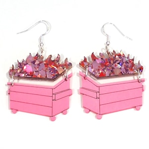 May include: Pink dumpster earrings with a glittery red and pink fire on top. The earrings are made of acrylic and have silver hooks.