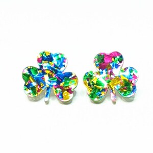 May include: A pair of iridescent green shamrock earrings with a multi-colored glitter finish.