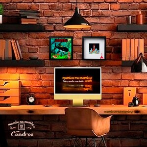 May include: A computer monitor displaying the text mambo na mambo .com on a desk in front of a brick wall. Two framed prints are mounted on the wall above the monitor, one featuring a submarine and the other a red rocket ship illustration.