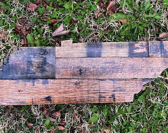 May include: A wooden outline of the state of Tennessee, made from reclaimed wood planks. The wood is stained in shades of brown and black, with some of the planks showing the original grain of the wood.