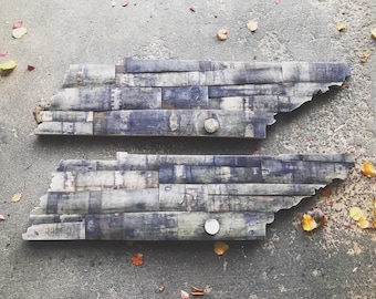 May include: Two pieces of wood, arranged in the shape of the state of Tennessee, are made from reclaimed wood planks. The wood is a dark brown color with a weathered look.