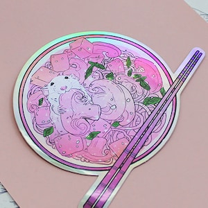 May include: A holographic sticker of a pink bowl of ramen with a small white mouse inside. The bowl is topped with green onions and pink tofu. Two chopsticks are included in the sticker.