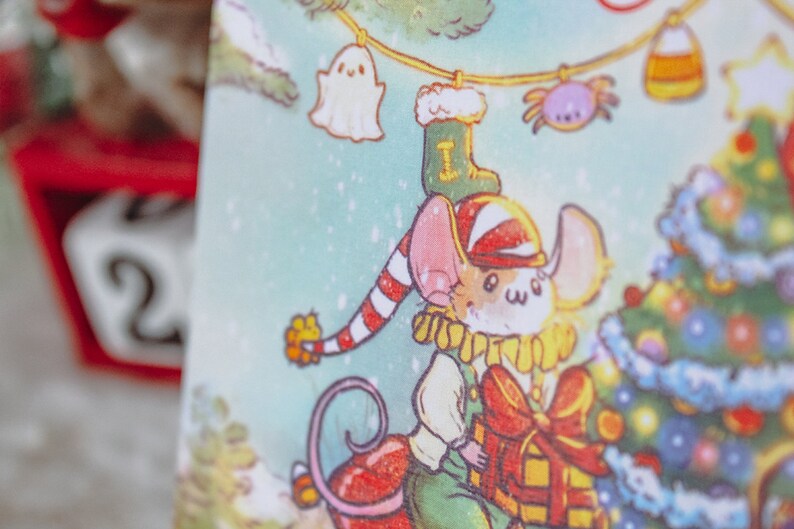 May include: A cartoon mouse wearing a red and white striped hat and a green and yellow outfit holds a red and yellow gift box. The mouse is standing in front of a decorated Christmas tree with ornaments and lights. The background is a light blue with snowflakes.