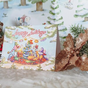 May include: A Christmas card with a winter scene featuring three mice dressed in festive attire. The card reads "Happy Holidays" and features a Christmas tree, presents, and a candy cane.