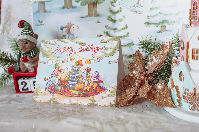 May include: A Christmas card with a winter scene featuring three mice dressed in festive attire. The card reads "Happy Holidays" and features a Christmas tree, presents, and a candy cane.