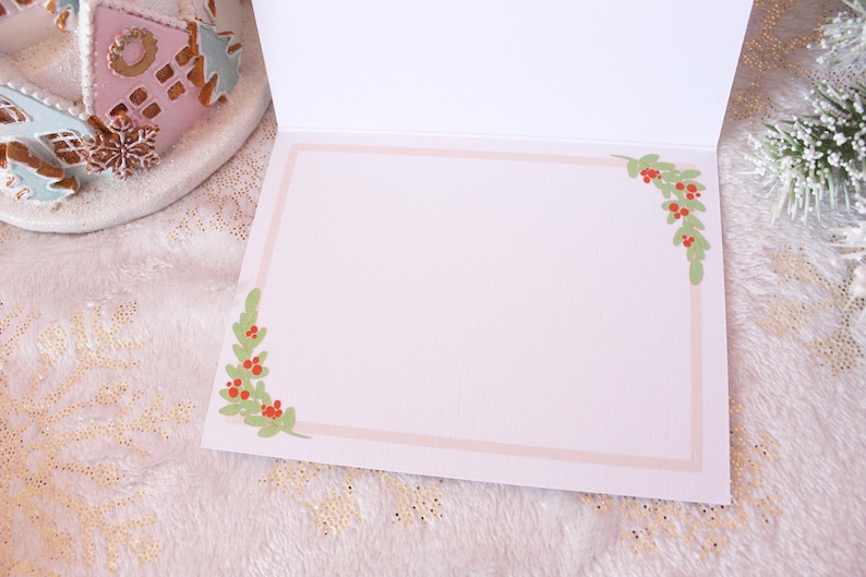 May include: Blank white card with a pink border and green holly sprigs with red berries in each corner.