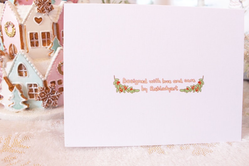 May include: A white card with a pink border and a green and red floral design. The text "Designed with love and care by Ratladyart" is printed on the card.