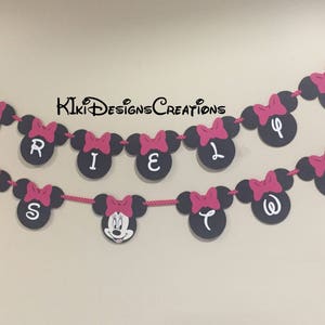 May include: A black and white Minnie Mouse themed banner with pink bows and the word "Riley is Two" in white letters.