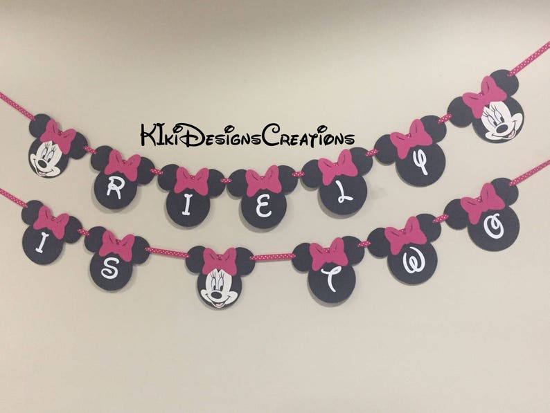 May include: A black and white Minnie Mouse themed banner with pink bows and the word "Riley is Two" in white letters.