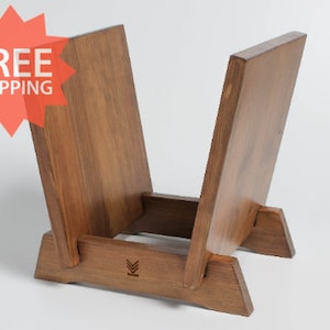 May include: A wooden record stand with two shelves, made of dark brown wood. The stand has a simple design with a small logo on the front.