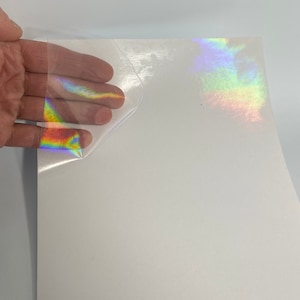 Op de afbeelding: Een vel holografisch vinyl met een regenboogkleurige effect. Het vinyl wordt teruggetrokken om de kleeflaag eronder te onthullen.