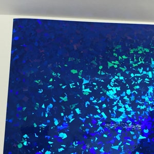 K&ouml;nnte beinhalten: Eine Folie aus irisierendem blauem Material mit einem Streumuster aus geometrischen Formen in Blau- und Gr&uuml;nt&ouml;nen. Die Oberfl&auml;che reflektiert das Licht und erzeugt einen schimmernden Effekt.