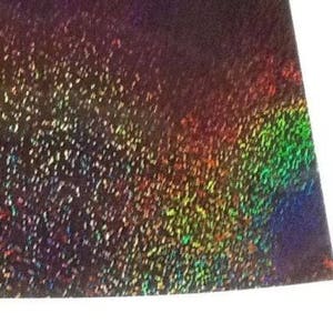 May include: A sheet of iridescent holographic paper with a dark purple base and a rainbow sheen. The paper has a speckled texture.