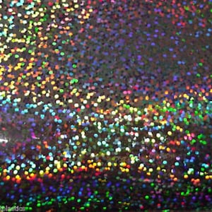 May include: A close-up of iridescent silver fabric with a holographic finish. The fabric is covered in small, round, multi-coloured sequins.
