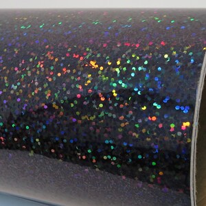May include: A roll of black iridescent glitter vinyl with a holographic finish. The vinyl has a textured surface with small, round glitter particles.