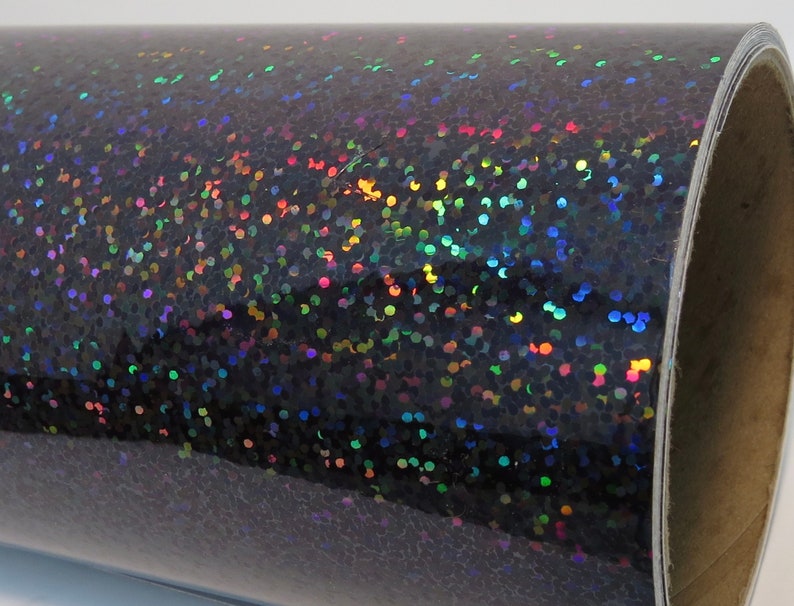 May include: A roll of black iridescent glitter vinyl with a holographic finish. The vinyl has a textured surface with small, round glitter particles.