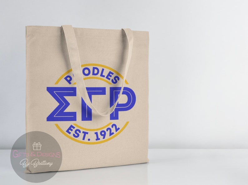 May include: A beige canvas tote bag with blue and gold lettering. The lettering reads "Poodles &Sigma;TP Est. 1922".