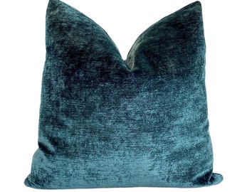 May include: Teal blue velvet pillow with a textured, slightly distressed look. The pillow is square and has a simple design.
