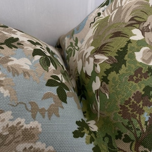May include: Two decorative throw pillows with a floral pattern in shades of green, brown, and blue. The fabric has a textured weave.