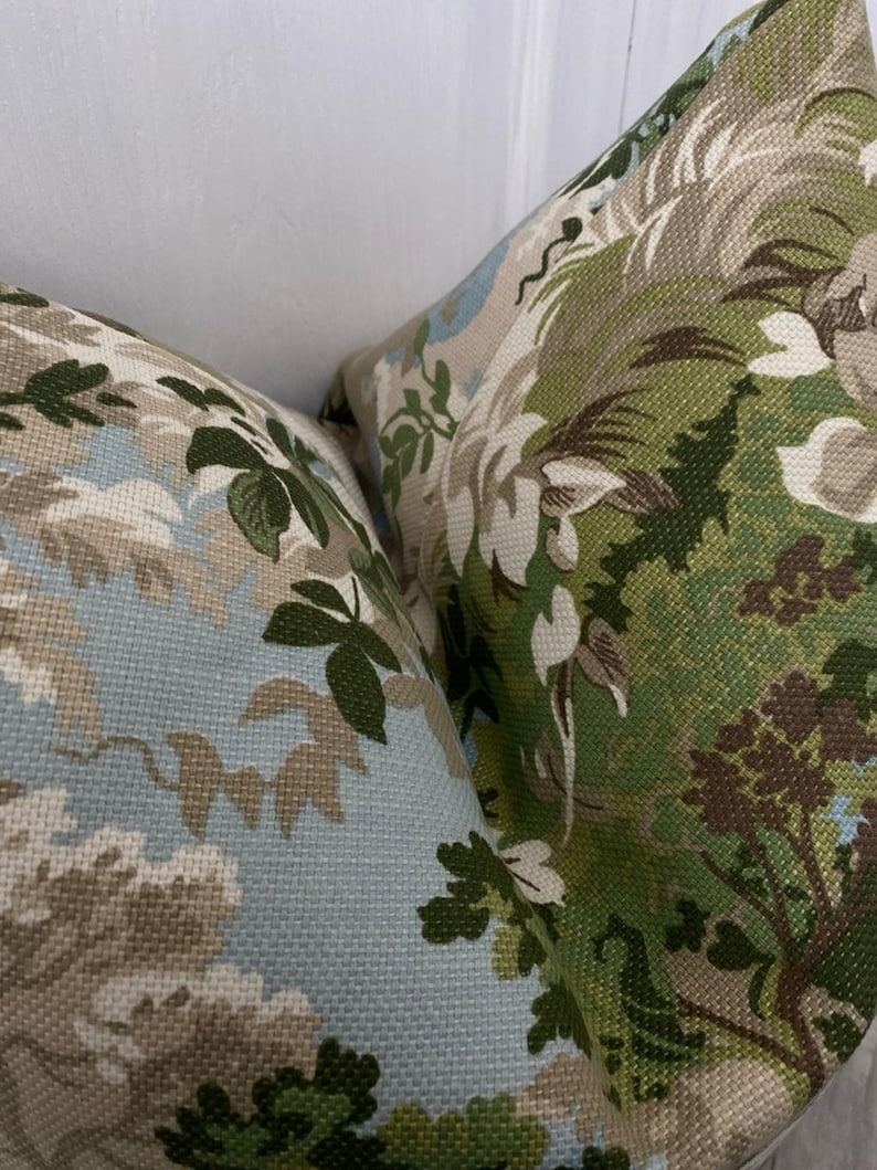 May include: Two decorative throw pillows with a floral pattern in shades of green, brown, and blue. The fabric has a textured weave.
