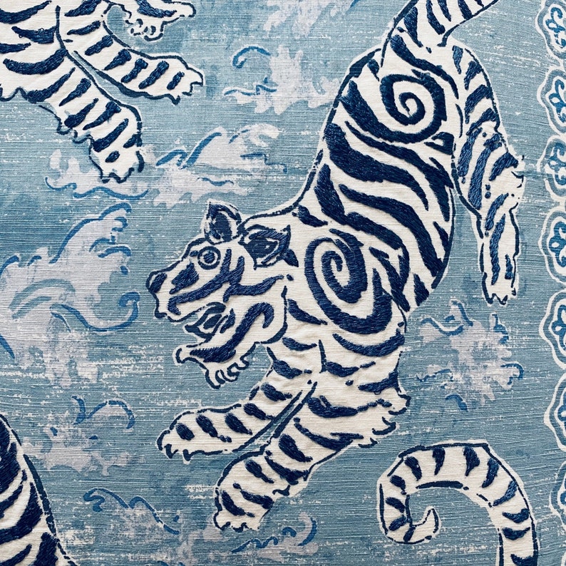 May include: A blue and white fabric with a repeating pattern of tigers. The tigers are stylized and have a swirling pattern on their bodies.